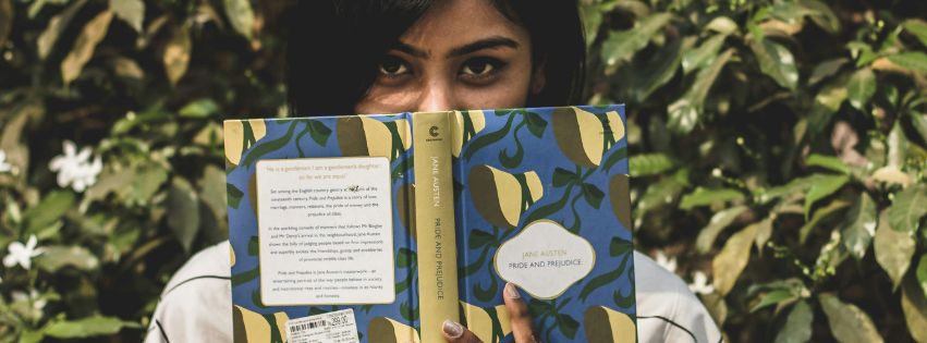 woman holding jane austen book in front of greenery