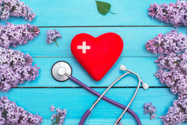 health symbols - heart with cross on it and stethoscope - surrounded by spring flowers