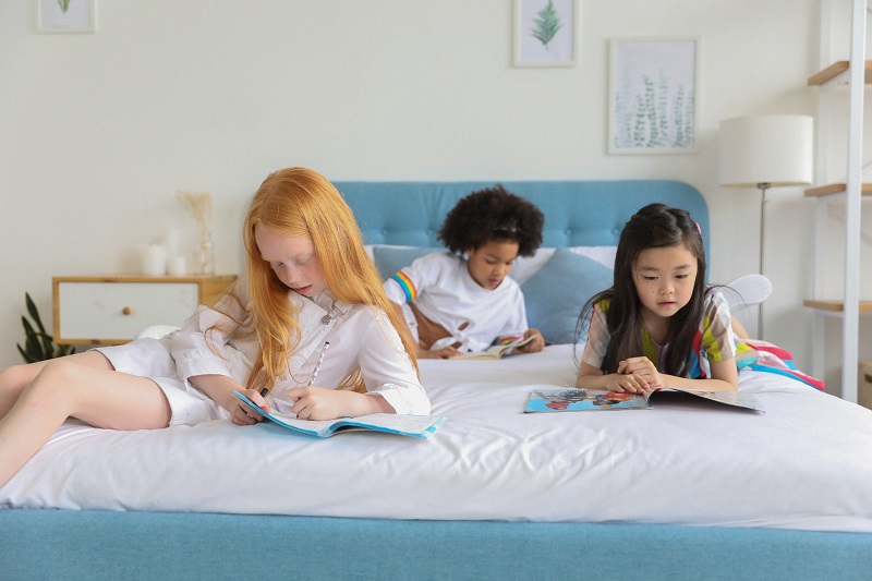 diverse girls reading books on bed