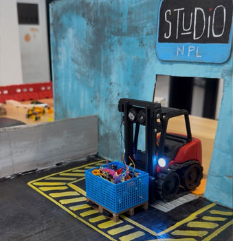 3D printed truck at Studio NPL driving through a blue gate down a ramp.