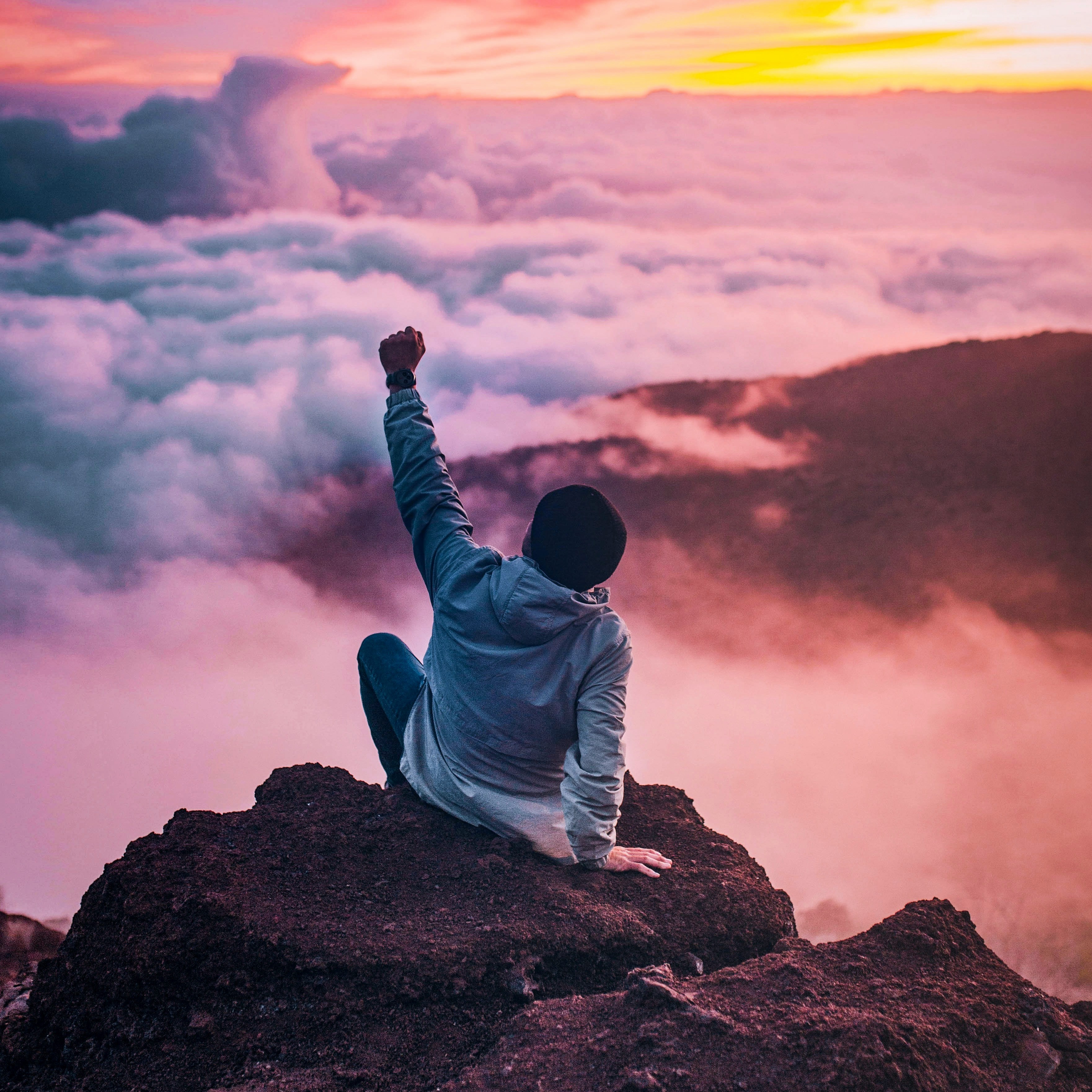 a child on a rock amongst waves with fist pumped high in success