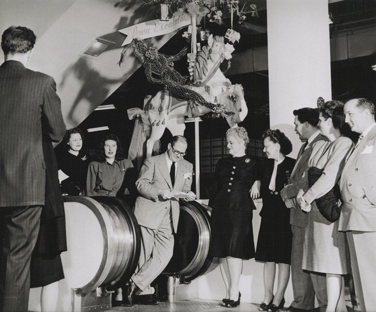Photo of Harvey's staff standing around for a meeting near their elevators, with one of the iconic carousel horses in the background
