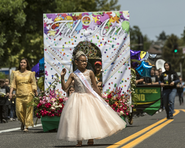 Photo shows a parade float with girl standing in front. 