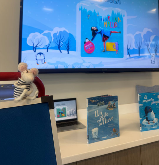 Buttercup sitting on a book cart at Spanish storytime.