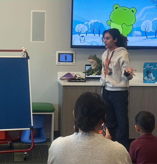 Buttercup and Miss Sol with her frog puppet Kiwi during storytime.