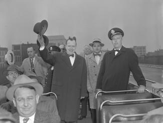 Mayor West waves to the camera while riding on the See Cruiser, over the Victory Memorial Bridge, circa 1956