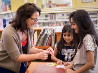 woman helping two young library visitors